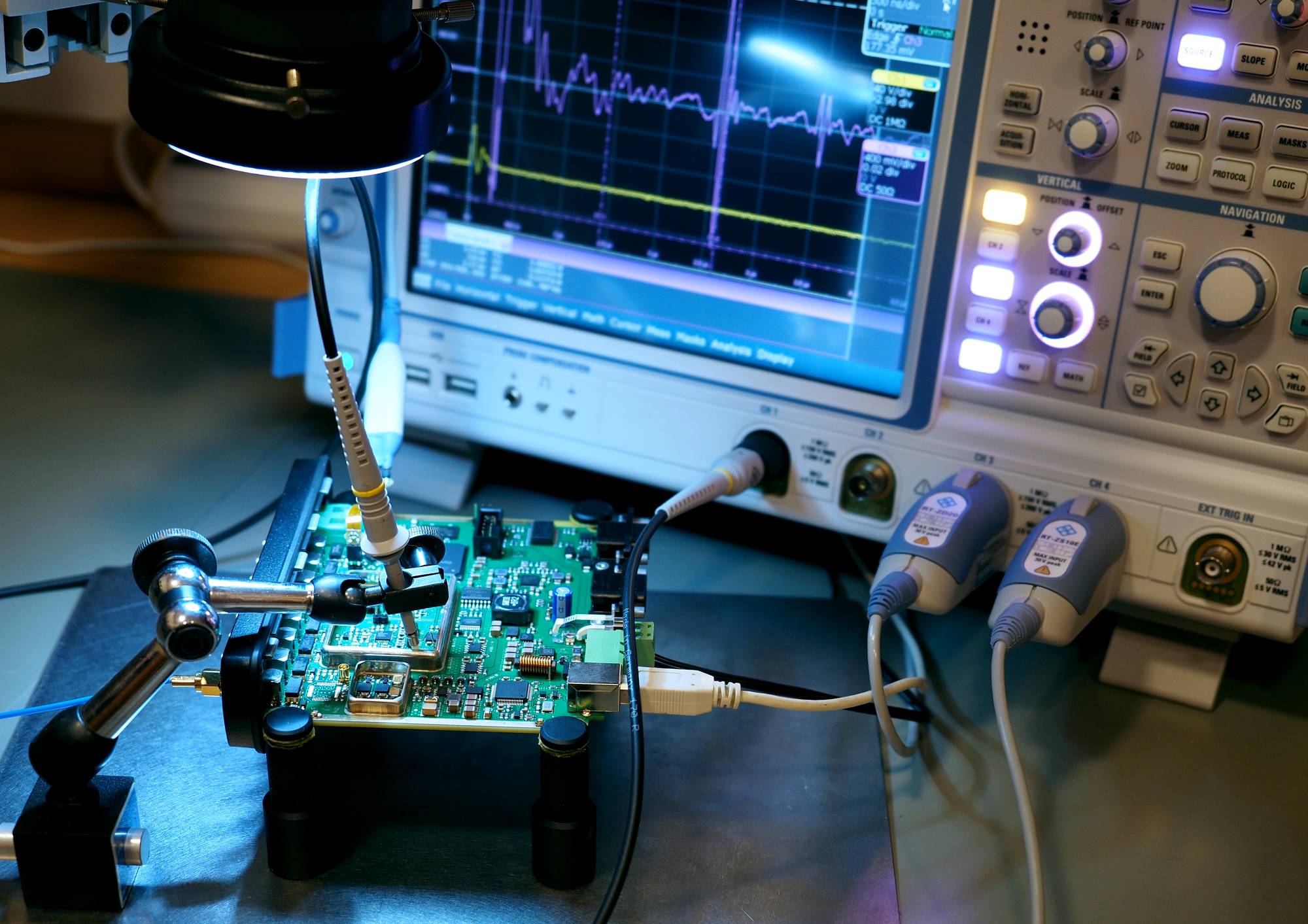 Leiterplatte mit elektronischen Bauteilen, Oszilloskop und Tastkopf